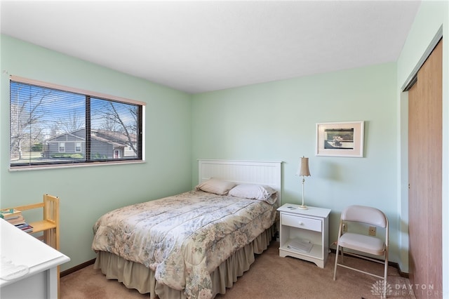 bedroom with a closet, light carpet, and baseboards