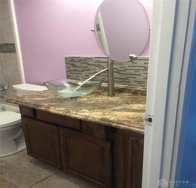 full bathroom with tasteful backsplash, toilet, and vanity