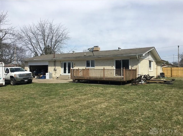 rear view of property with fence, an attached garage, french doors, a deck, and brick siding