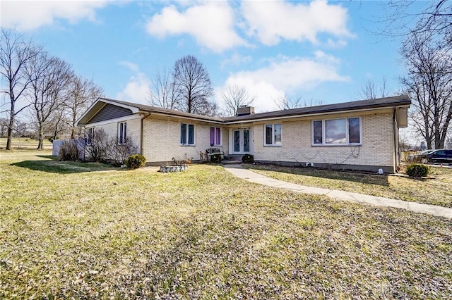 view of front of property featuring a front yard, french doors, brick siding, and a chimney