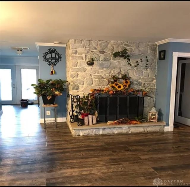 interior space featuring a stone fireplace, wood finished floors, and crown molding