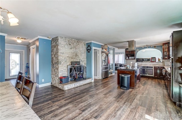 kitchen with appliances with stainless steel finishes, a center island, dark wood-style flooring, and crown molding