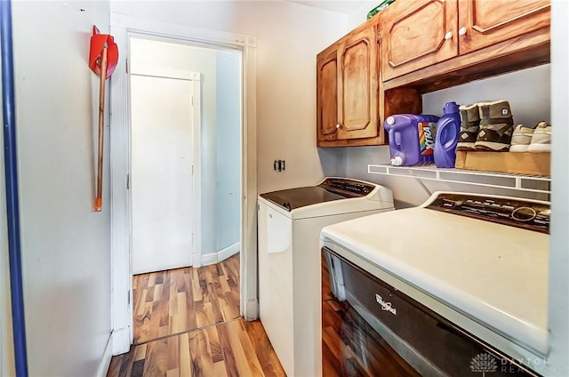 laundry room featuring washer and clothes dryer, cabinet space, and light wood-style floors