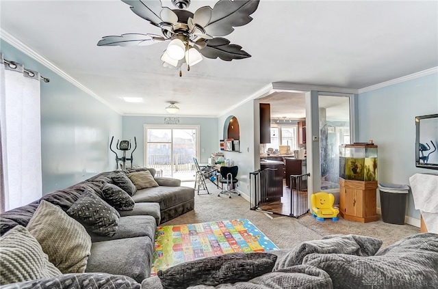 carpeted living area with arched walkways, ceiling fan, and crown molding