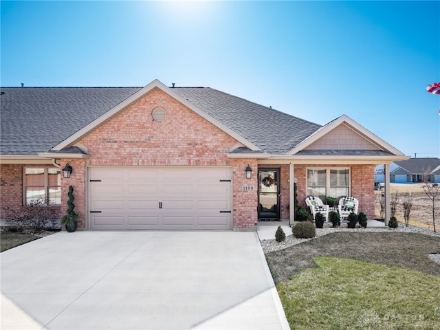 single story home with driveway, covered porch, a shingled roof, a garage, and brick siding