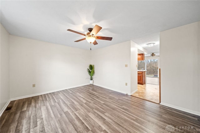 empty room with baseboards, wood finished floors, and ceiling fan