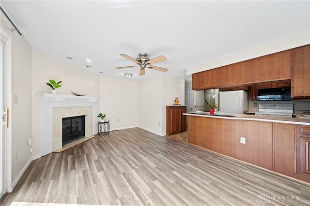 kitchen with brown cabinets, range with electric stovetop, freestanding refrigerator, and black microwave