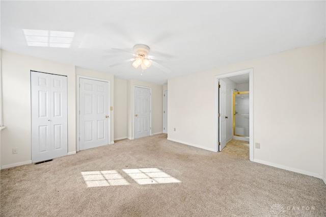 unfurnished bedroom featuring ceiling fan, baseboards, carpet, and multiple closets