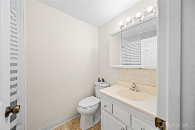 bathroom featuring toilet, vanity, and baseboards