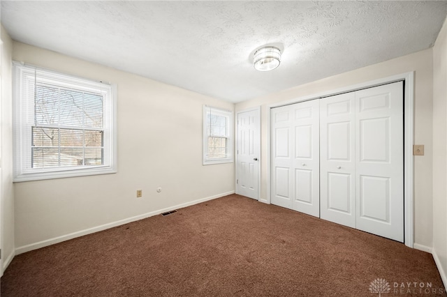 unfurnished bedroom with visible vents, a textured ceiling, baseboards, and carpet floors