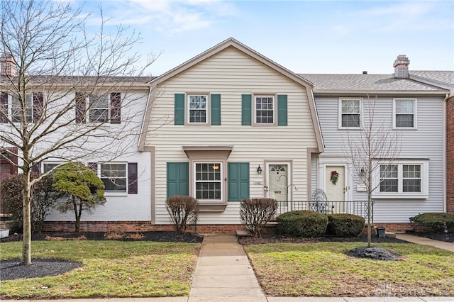 townhome / multi-family property with a chimney and a front lawn