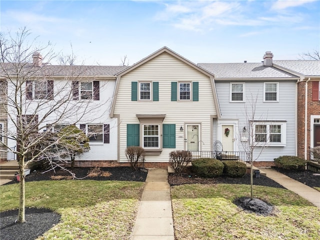 multi unit property with a shingled roof, a front yard, and a chimney