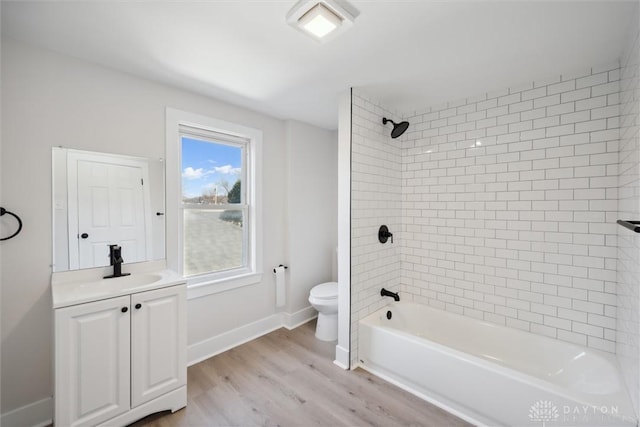 bathroom with vanity, wood finished floors, baseboards, bathing tub / shower combination, and toilet