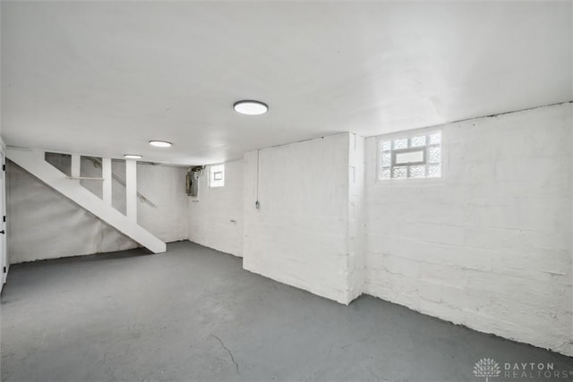 below grade area featuring plenty of natural light, concrete block wall, and stairs