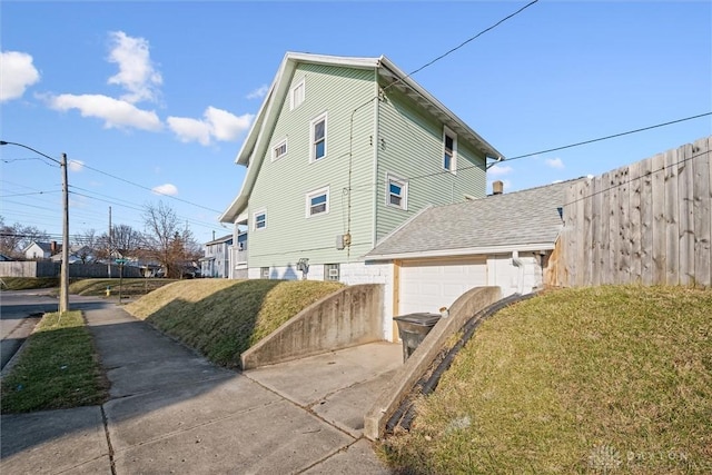 view of side of home featuring concrete driveway, fence, a garage, and a lawn