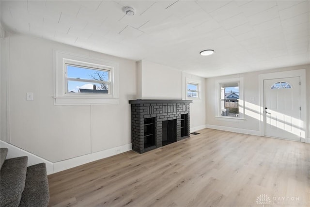 living room with stairway, light wood-style flooring, a fireplace, and baseboards