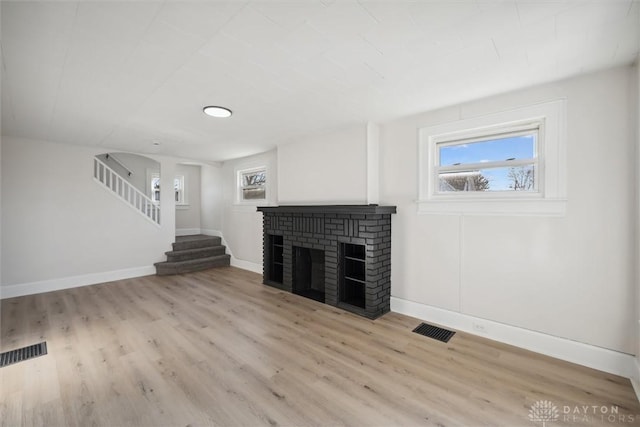 unfurnished living room featuring a fireplace, light wood-style floors, and visible vents