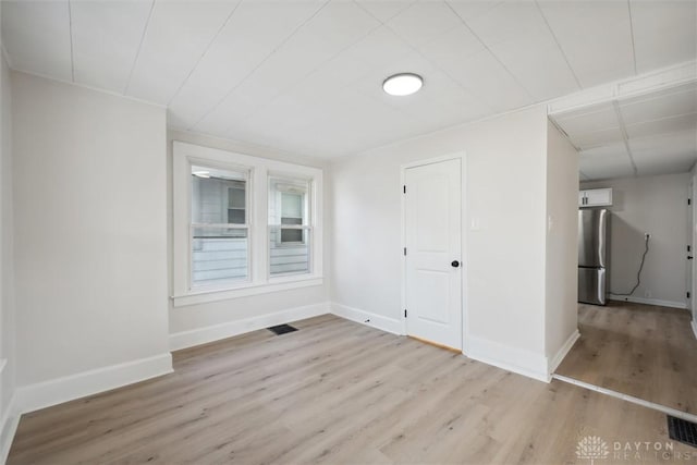 unfurnished room featuring visible vents, baseboards, and wood finished floors