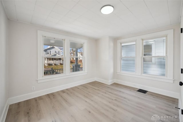 empty room with wood finished floors, baseboards, and visible vents