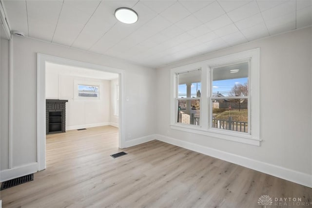 spare room featuring a fireplace, visible vents, and light wood finished floors