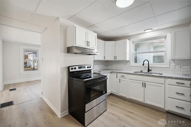 kitchen featuring electric range, visible vents, under cabinet range hood, a sink, and backsplash