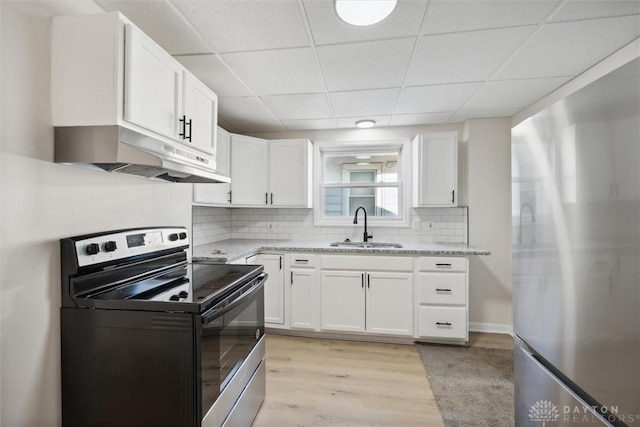 kitchen featuring under cabinet range hood, freestanding refrigerator, electric range, white cabinets, and a sink