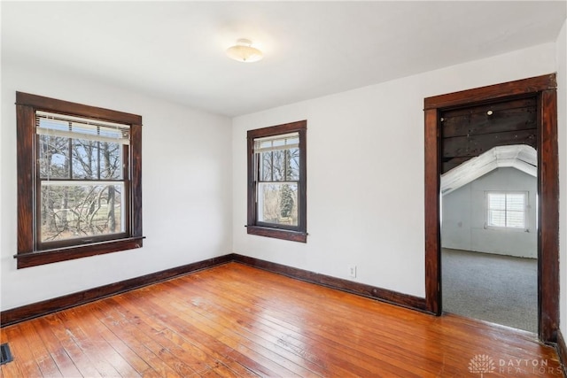 unfurnished room featuring visible vents, baseboards, and hardwood / wood-style flooring