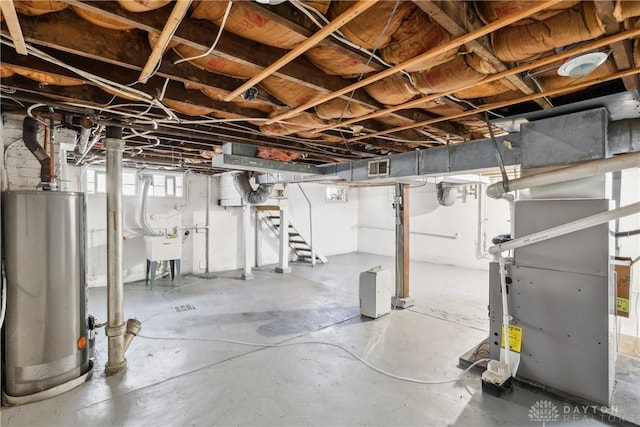 below grade area featuring heating unit, visible vents, water heater, a sink, and stairs