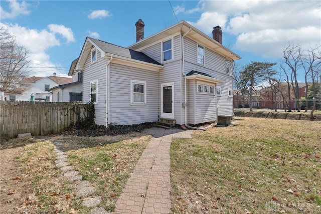 rear view of property featuring central air condition unit, entry steps, a chimney, and fence