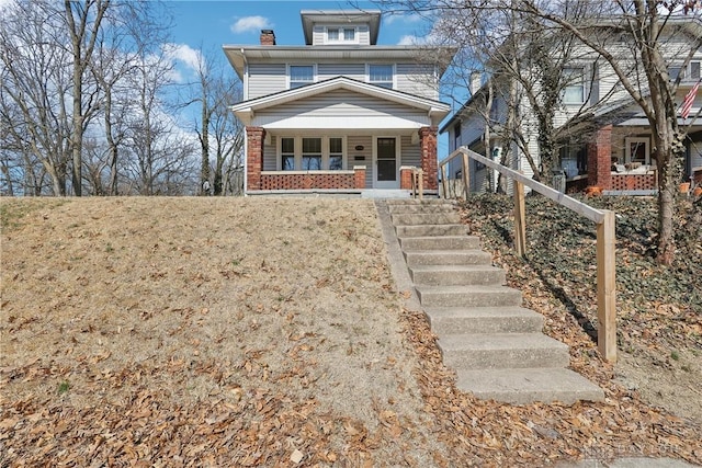 view of front of property with a porch, brick siding, and a chimney