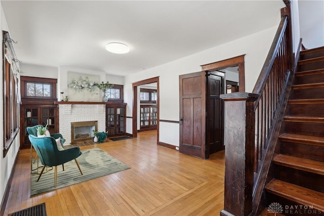 living area featuring light wood finished floors, visible vents, baseboards, stairs, and a fireplace