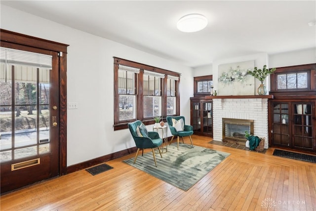 foyer entrance with hardwood / wood-style flooring, a brick fireplace, baseboards, and visible vents