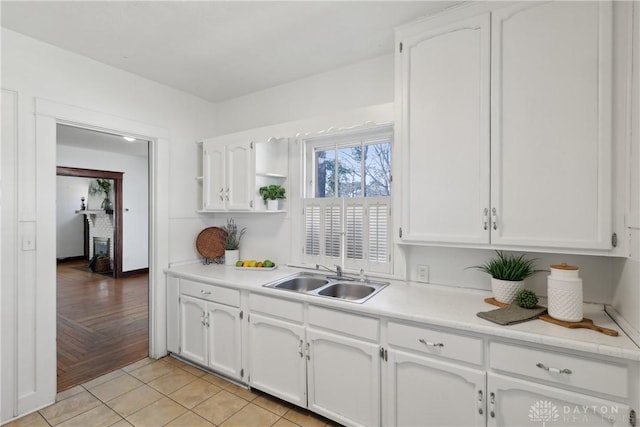 kitchen featuring open shelves, white cabinetry, light countertops, and a sink