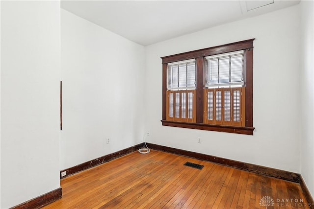 empty room featuring visible vents, baseboards, and hardwood / wood-style floors