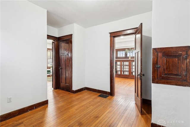 empty room with baseboards, visible vents, and light wood finished floors