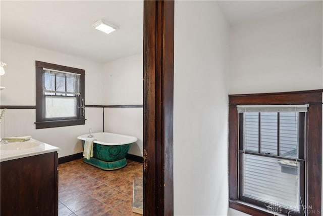 bathroom featuring tile patterned flooring, a soaking tub, vanity, and baseboards