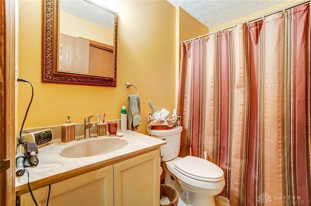 full bathroom with vanity, toilet, and a textured ceiling