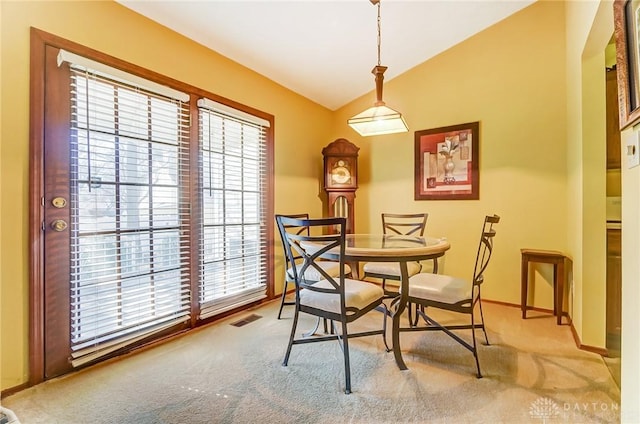 carpeted dining space with visible vents, baseboards, and vaulted ceiling