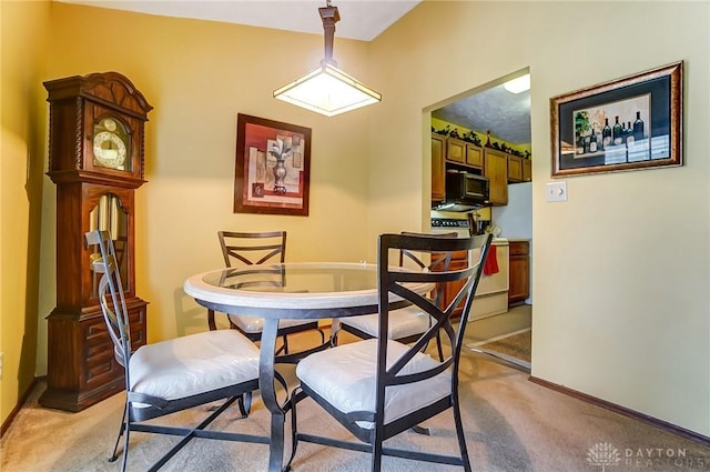 dining space with baseboards and light carpet