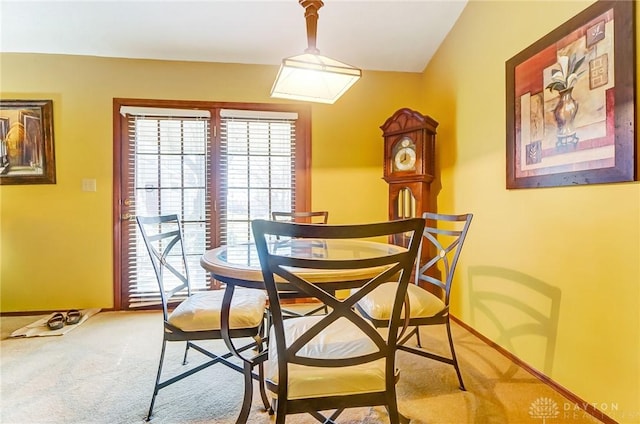 dining space featuring light colored carpet and baseboards