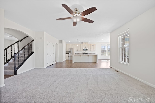 unfurnished living room with carpet flooring, baseboards, and a ceiling fan