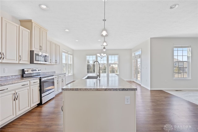 kitchen featuring dark wood-type flooring, a chandelier, an island with sink, stainless steel appliances, and a sink