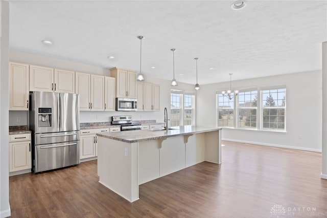 kitchen featuring dark wood-style floors, a breakfast bar, a sink, appliances with stainless steel finishes, and a chandelier