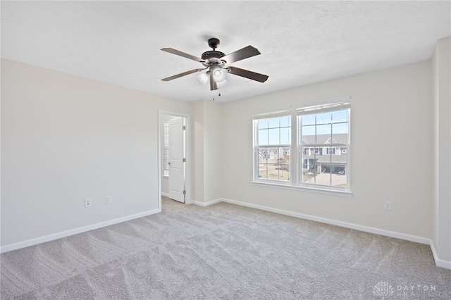 carpeted spare room with baseboards, a textured ceiling, and a ceiling fan