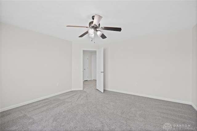 carpeted empty room featuring baseboards and ceiling fan