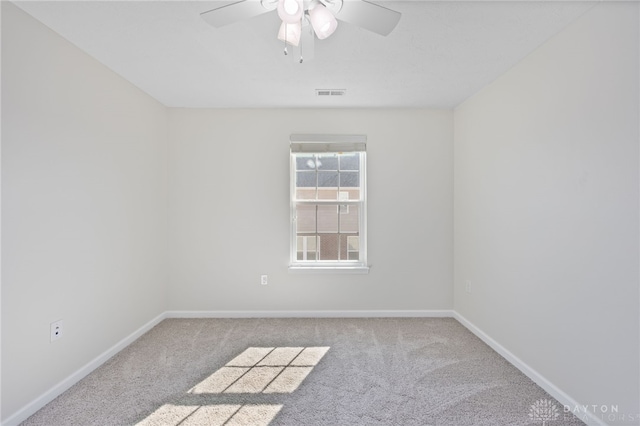 carpeted empty room featuring a ceiling fan, visible vents, and baseboards