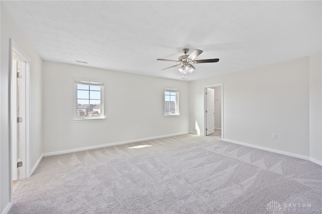 empty room with baseboards, light colored carpet, ceiling fan, and a textured ceiling