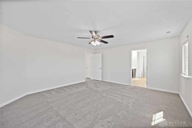 unfurnished room featuring baseboards, visible vents, a ceiling fan, and carpet