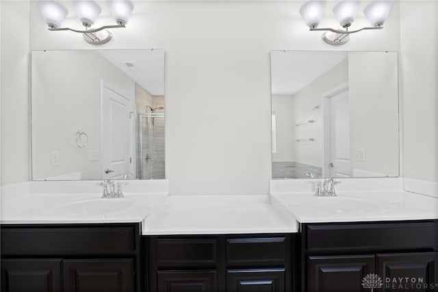 bathroom with an inviting chandelier, double vanity, a stall shower, and a sink