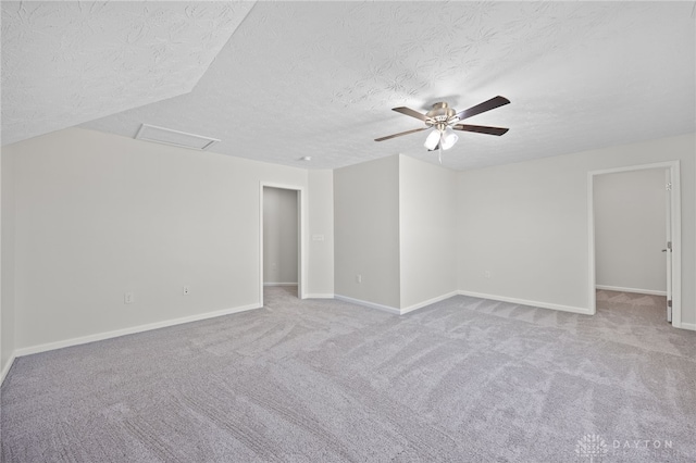 spare room with a ceiling fan, baseboards, attic access, a textured ceiling, and carpet flooring